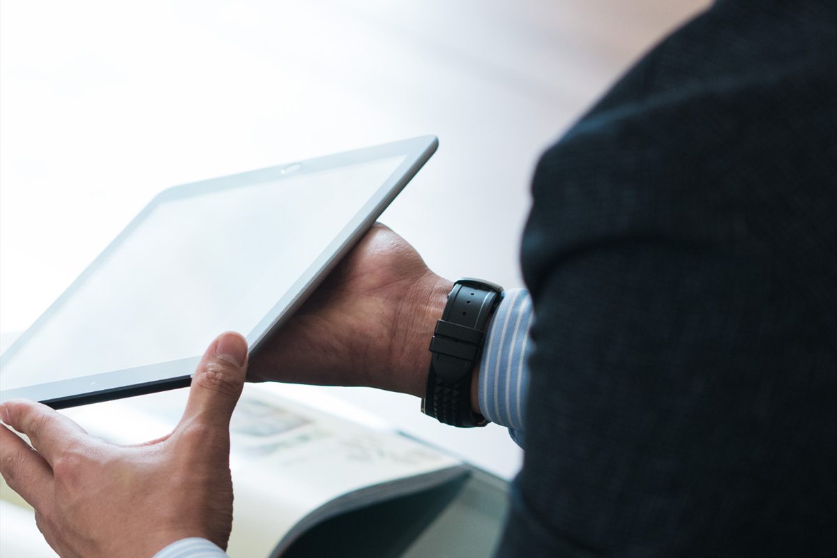 Mains d'un cadre en costume consultant une tablette et des documents