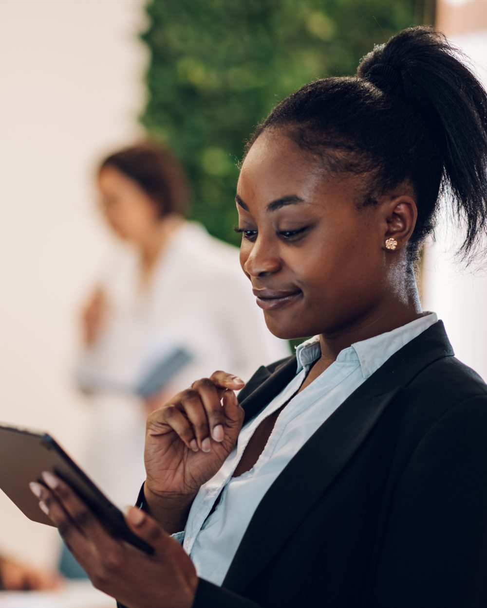 Chargée de clientèle en tailleur consultant une tablette dans un bureau
